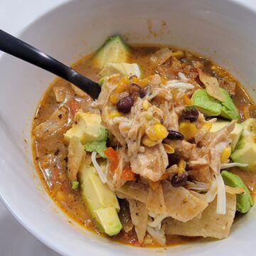 bowl of tortilla soup with avocado, beans and chips