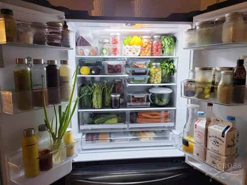 An open fridge with produce in assorted jars and containers