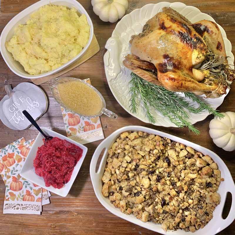 BlogPost_014 - 03 - Whole Roasted Turkey, Thanksgiving Stuffing, Cranberry Sauce, Gravy and Mashed Potatoes laid out on a table.