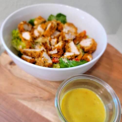 chicken strips on a salad with dressing on counter