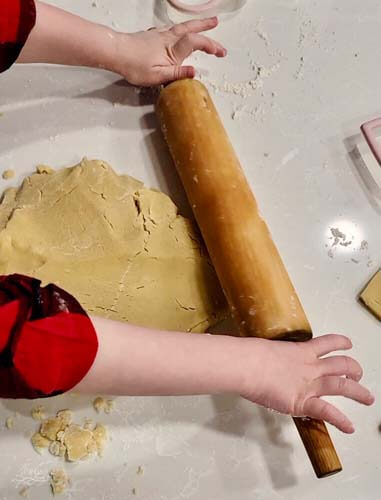 young helper assisting in rolling out sugar cookie dough
