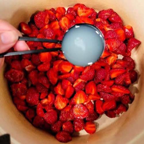 pouring-sugar-onto-cut-strawberries-in-a-bowl
