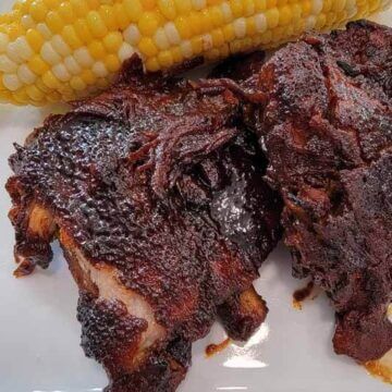 spare ribs with sweet and smokey rub and BBQ sauce and corn on the cob on a white plate