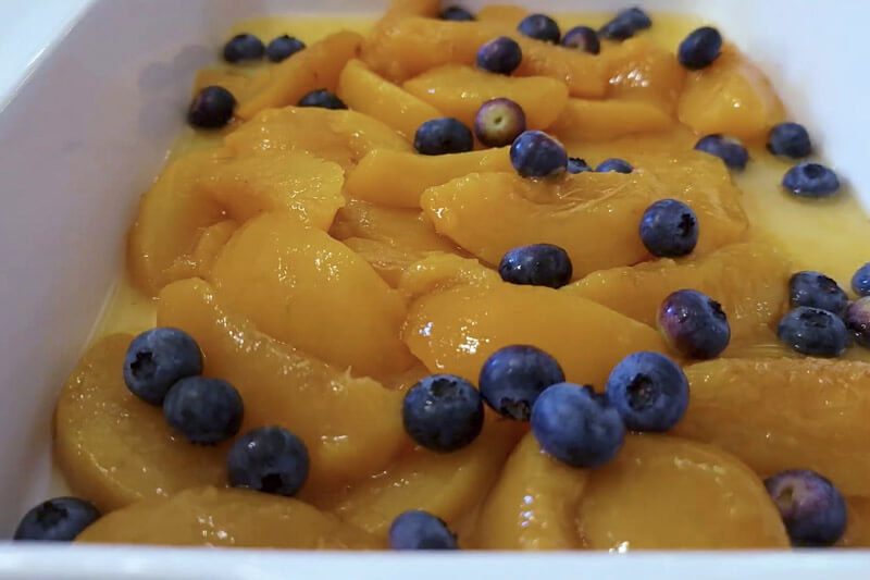 Raw blueberries and peaches in a baking dish