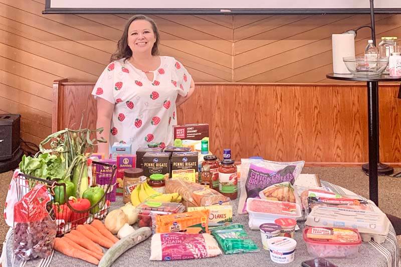Amy on the stage of her Step-by-Step event with $135 worth of groceries