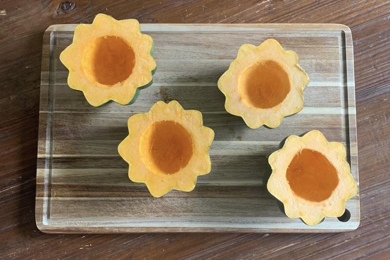 Two squash boats sitting on a wooden cutting board.