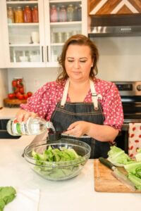 Amy in her kitchen adding vinegar to to the bowl of water to wash romaine lettuce.