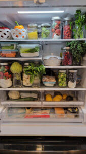 Amy's December fridge pic filled with fresh produce in glass containers.