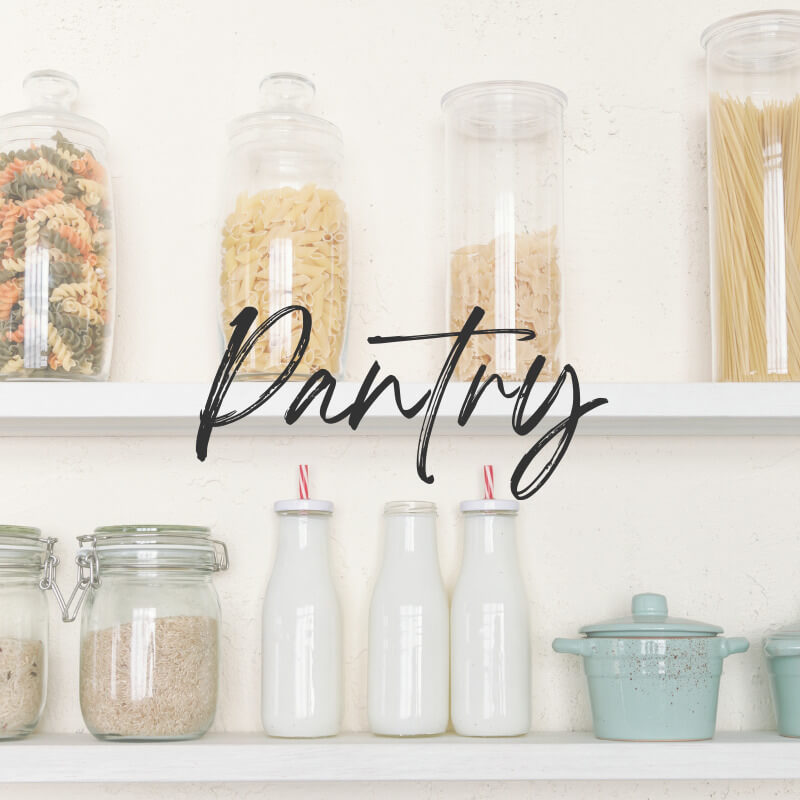 White pantry shelves with glass jars containing grains and pasta. Three white ceramic bottles, and 3 aqua crocks with lids. Category Page Featured Image for Pantry page.