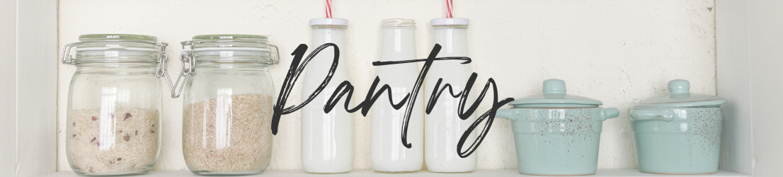 White pantry shelves with glass jars containing grains and pasta. Three white ceramic bottles, and 3 aqua crocks with lids. Category Page Header Image for Pantry page.